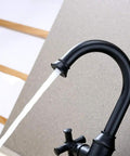 Matte Black Two Handle Bathroom Sink Faucet With 360 Degree Swivel Spout For 1 Hole Vanities Drip Free Ceramic Cartridge Solid Brass Waterway Includes Water Supply Line Easy Install, side view with running water