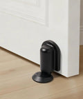 Matte Black Magnetic Door Stopper Holds Interior Doors Firmly Open Heavy Duty Floor Mounted Catch With Screw Or Adhesive Install Skip The Loud Slam Forever, close-up view on hardwood floor.