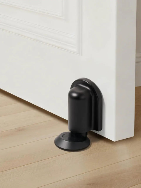 Matte Black Magnetic Door Stopper Holds Interior Doors Firmly Open Heavy Duty Floor Mounted Catch With Screw Or Adhesive Install Skip The Loud Slam Forever, close-up view on hardwood floor.