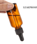 Close-up of hand holding one bottle from the 4 Pack 30ml Dark Amber Glass Dropper Bottles With 1 Funnel And 4 Labels, marked leakproof.