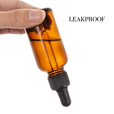 Close-up of hand holding one bottle from the 4 Pack 30ml Dark Amber Glass Dropper Bottles With 1 Funnel And 4 Labels, marked leakproof.