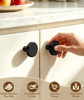 Top Tier Heavy Duty Black Cabinet Knobs Slick Round Handles For Kitchen Cupboards And Drawers Solid Zinc Alloy Hardware Built Tough Quick Install Hassle Free Setup Dependable Twenty Pack Bundle. Hand reaching for a smooth black zinc alloy cabinet knob on kitchen cupboard.