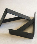 Heavy Duty Wall Mounted Shelf Brackets With Bullet Proof Triangular Steel Frame For Countertops And Floating Shelves Rust Resistant Matte Black Finish, angled view on light surface.