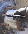 Close-up of a steel vehicle wheel hub with rusted lug studs; gloved hand uses a GAITHER tool.