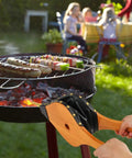 Badass Heavy Duty Oak Wood Fire Bellow For Starting Campfires And Grilling Coals Fast With A Dope Grip in use at a barbecue.
