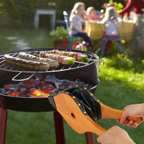 Badass Heavy Duty Oak Wood Fire Bellow For Starting Campfires And Grilling Coals Fast With A Dope Grip in use at a barbecue.