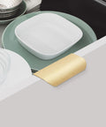 Gold Adhesive Edge Finger Pulls for Cabinets installed on drawer, 3.15 inch length, brushed gold finish, with dishes inside.