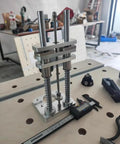 Compact Drill Press Stand With Vertical Drill Guide for Hand Drills, sturdy aluminum, on workshop bench for woodworking.
