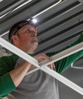 Worker wearing Rechargeable LED Headlamp With Adjustable Fabric Strap And Marker Holder for work and outdoors, installing ceiling frame.