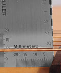 Close-up of a string action ruler measuring guitar strings, part of Guitar And Bass Setup Pro Tool Kit With 32 Blade Stainless Feeler Gauge Dual Metric And Imperial Markings Radius Gauges Understring Radius Guide Luthier Tools And String Action Ruler For Precise Fretboard And Neck Setup.
