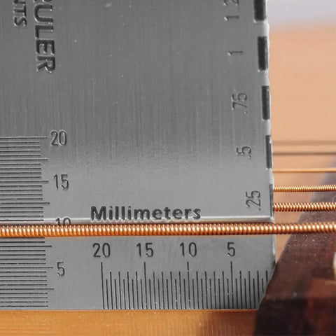 Close-up of a string action ruler measuring guitar strings, part of Guitar And Bass Setup Pro Tool Kit With 32 Blade Stainless Feeler Gauge Dual Metric And Imperial Markings Radius Gauges Understring Radius Guide Luthier Tools And String Action Ruler For Precise Fretboard And Neck Setup.