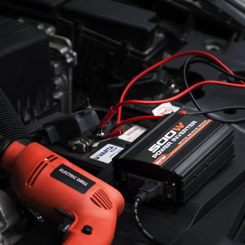 Ride Ready 500W Car Power Inverter Converts 12V DC To 110V AC With Dual USB Ports And Slick Compact Build To Keep All Your Devices Juiced Up While You Cruise On The Open Road, mounted on a car battery with red cables.