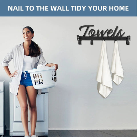 Woman in laundry room near black metal towel rack with 'Towels' sign, holding laundry basket; laundry decor setup idea.