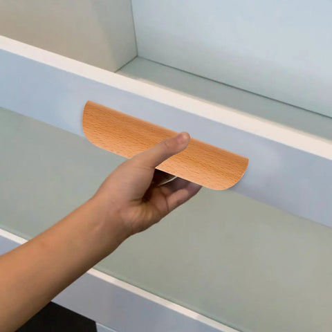 Hand holding semicircle solid wood cabinet handle 64mm beech from Set of 6, visible on kitchen wardrobe, sturdy furniture hardware