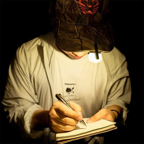 Dope 700 Lumen USB C Rechargeable EDC Flashlight clipped to cap, illuminating writing on a notebook in a dark setting