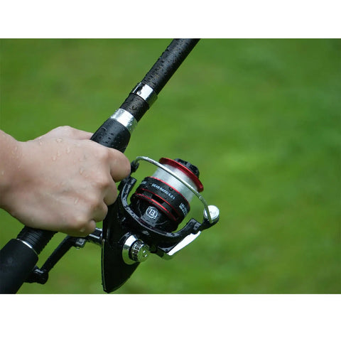 Close-up of hand holding a Two Piece Telescopic Fishing Rod Set With Carbon Fiber Poles, Six Point Nine Foot Length, with spinning reel
