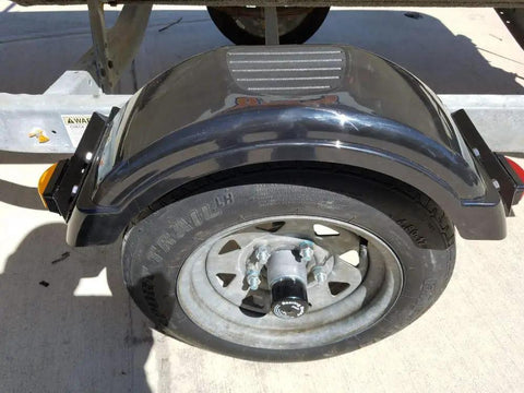 Close-up of a trailer wheel with Trailer Hub Cap Protector In Stainless Steel Bearing Buddies, 1.98 Inch Diameter installed, outdoors