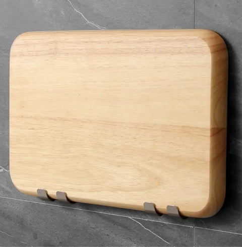 Wall-mounted wooden cutting board on gray tile wall with stainless steel hooks.
