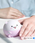 Cute pink and white contact lens cleaning machine shaped like a cat, held by a person, showing "Free Your Hand" text.