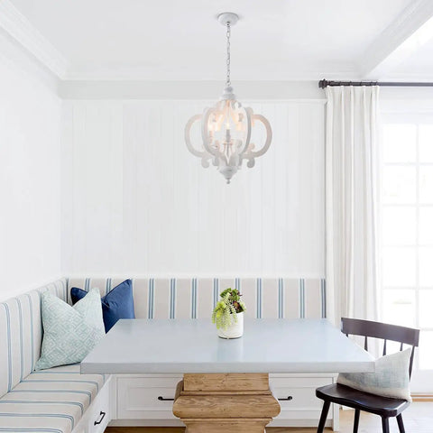 Farmhouse Six Light Wood Chandelier In Distressed White With Cozy Vibe And Warm Glow For Dining Room Kitchen Living Room Bedroom Hallway Cottage Pendant Light Vintage Rustic Style 21 Inch hanging above a rustic dining table with cushions in a bright room.