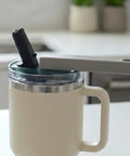 One Hand Tumbler Lid Opener With Ergonomic Lever Universal Fit For 20oz To 40oz Insulated Tumblers Like Stanley Hydrojug And Owala No Fuss Easy Grip Assisted Bottle Opener For Weak Hands Grey in use, shown on a beige insulated tumbler on a kitchen counter.