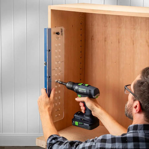 Person using Shelf Pin Drilling Jig For Cabinets And Woodworking With 1/4 Inch And 5mm Self Centering Bits on a wooden cabinet