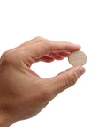 Hand holding a 1 inch unfinished round wood cookie from a 60 Pack 1 Inch Natural Wood Slices Unfinished Round Wood Cookies Real Deal Smooth Edged Pro Gear DIY Crafting Supplies Mini Wooden Disks For Paint Room Decor Makeovers.