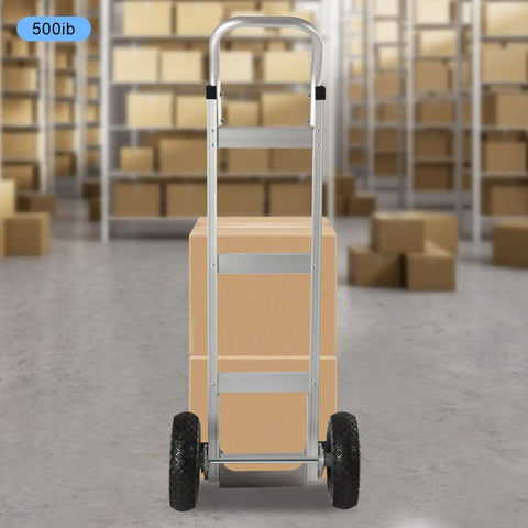 Heavy Duty Aluminum Hand Truck 500lbs Capacity Steel Handle Dolly Cart Horizontal Loop Design with cardboard boxes behind.
