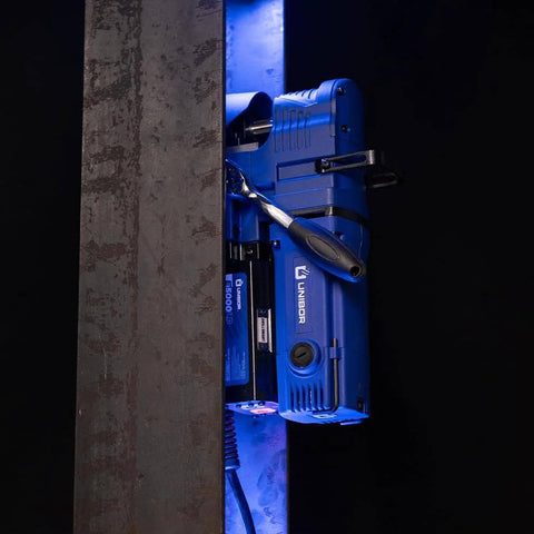 Unibor low-profile magnetic drill press, blue, mounted on a steel workpiece with LED light.