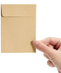 Person holding a brown seed packet, 4.5 by 3.25 inches, blank envelope for seeds, coins, keys, and tiny parts, DIY craft storage.