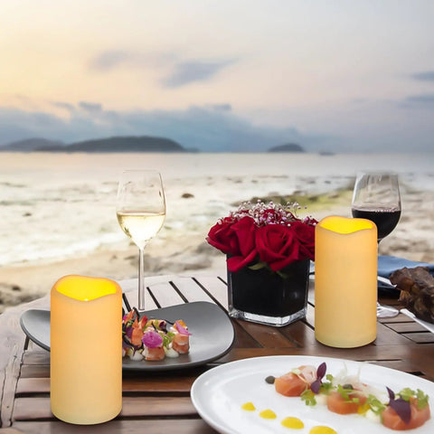 Waterproof Flameless LED Pillar Candles With Remote Timer Battery Operated Pack Of 3 on outdoor table at beach at sunset.