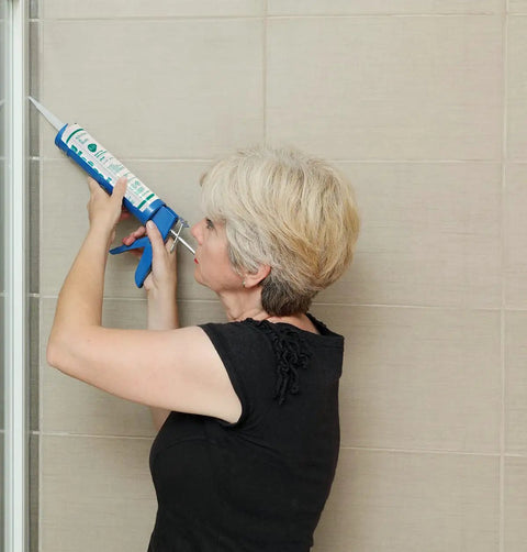 Person applying Ultimate 100 Percent Silicone Sealant For Kitchen And Bath, Waterproof, Low Odor, Clear Caulk on tile