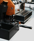 Kickstart Your Brew Routine With Top Shelf 58mm Bottomless Portafilter featuring aluminum handle near Breville espresso machine.