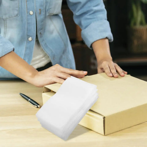 Person packing a box using Epe Foam Pouches 200 Pack For Moving And Shipping Cushioned Protection, stack of white foam sleeves nearby