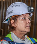 Side profile of a person wearing a white Hard Hat With Rechargeable Headlamp Mounts Front And Back Cap Style Vented Shell
