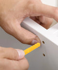 Hand inserting yellow plug from Yellow Plastic Wall Plugs Kit With Self Drilling Anchors 200 Piece Set For Hollow Walls Plasterboard.