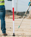 Built Tough Aluminum Prism Pole Shoe With Flat End For Precise Readings, shown on a field survey site, providing stability