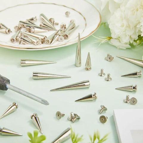 Killer Silver Cone Spike Studs 30 Piece Screw Back Rivet Kit 40Mm And 20Mm on a mint green surface with a screwdriver.