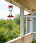 2 Pack 14 Ounce Plastic Hummingbird Feeders With Ant Moat And Bee Guard For Outdoors hanging on porch