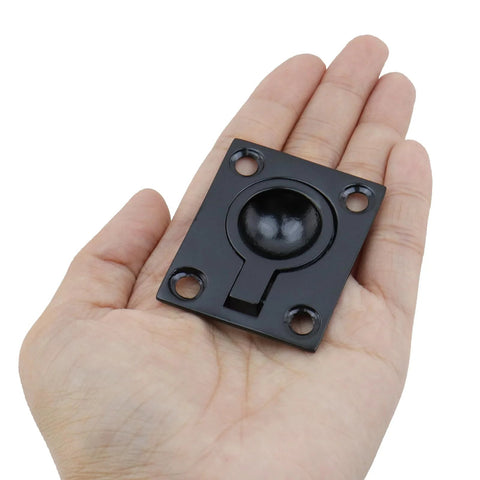 Close-up of black square flush hatch pull handle with central dome and four mounting holes
