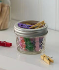 Wide Mouth Quilted Crystal Jelly Jars With Lids And Bands For Canning, Juices, Jams, pack of 6 on shelf with colored clothespins inside