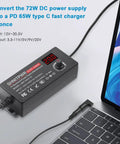 Universal 72W Power Supply With Adjustable 3V To 24V DC Output And 3A Cable next to a laptop with LCD display showing voltage.