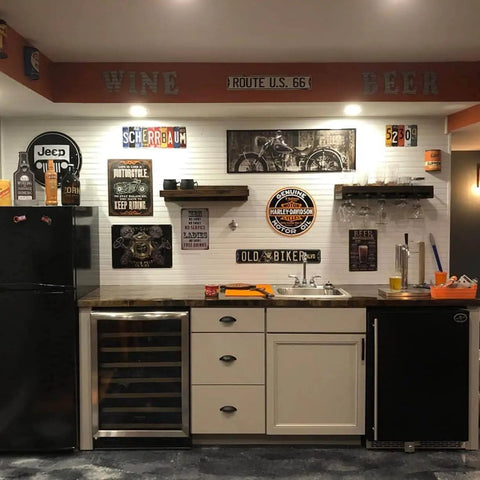 Rustic kitchen decor with vintage tin signs and memorabilia on wall above counter with cabinets and mini-fridge.