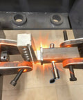 Metal testing process showing clamps and equipment in an industrial setting, focusing on structural stress points and durability.