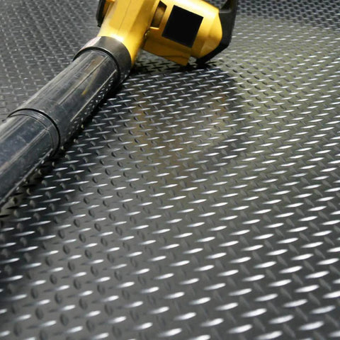 Diamond Plate Rubber Flooring Roll 3 mm Thick 4 Ft By 2 Ft Black Durable Industrial Grippy Floor Mat for Slippery Surfaces Outdoor Walkways and Equipment Protection with a yellow device on top.