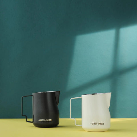 12 Oz Stainless Steel Milk Frothing Pitcher For Espresso And Latte Art Black Round Spout Milk Jug Durable Barista Grade Foam Maker Turbo Design For Rich Microfoam And Silky Smooth Latte next to a white jug.