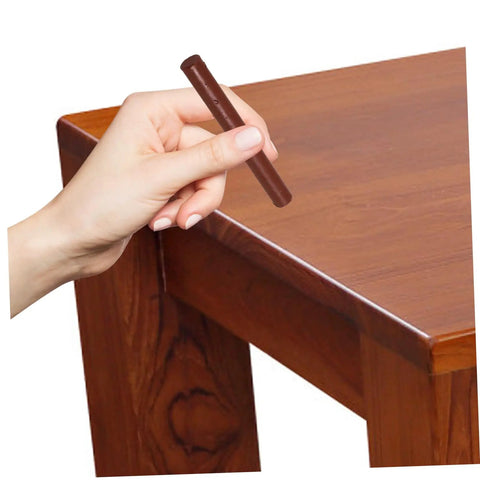 Hand applying Dark Brown Wood Repair Kit Wax Filler Stick on a wooden table surface for Easy To Use No Mess Scratch Repair.