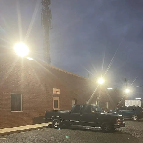 LED Parking Lot Light 150W Outdoor Floodlight illuminating cars in a commercial parking area at dusk, IP65 weatherproof.