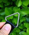 Hand holding Marine Grade Stainless Steel 316 Triangle Ring Buckle Welded V Shaped Ring against green leaves background.