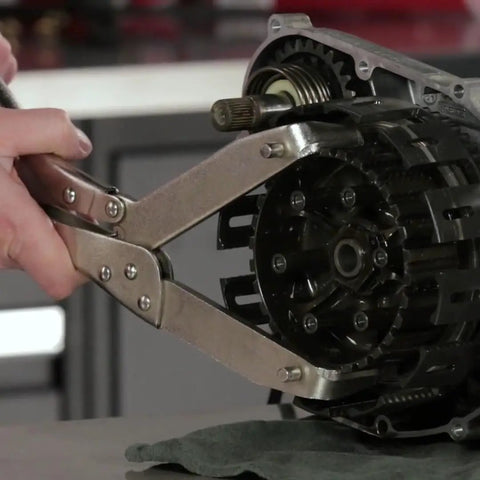 Universal Motorcycle Clutch Flywheel Holding Tool Engine Repair Fixture shown in use clamping clutch basket gear for maintenance.